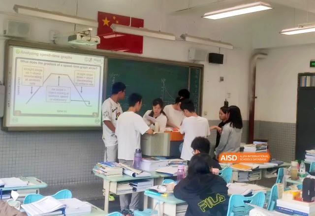 Students gather around a desk to collaborate on a hands-on project in a vibrant and interactive classroom setting at Zhengzhou No.1 High School