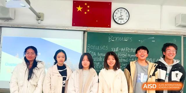 Three female students stand together in front of a chalkboard featuring academic notes and a national flag at Zhengzhou No.1 High School