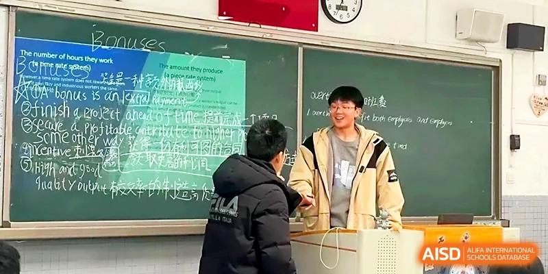 Two students interact and smile during a peer-led presentation or collaborative classroom activity at Zhengzhou No.1 High School