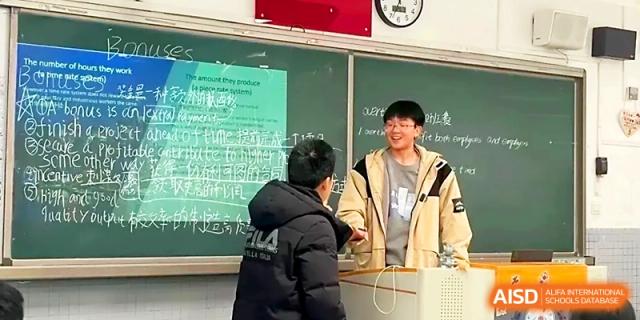 Two students interact and smile during a peer-led presentation or collaborative classroom activity at Zhengzhou No.1 High School