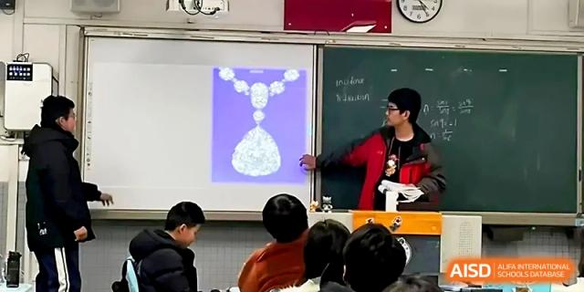 A student points to a projector screen displaying a diamond necklace during a classroom lesson at Zhengzhou No.1 High School