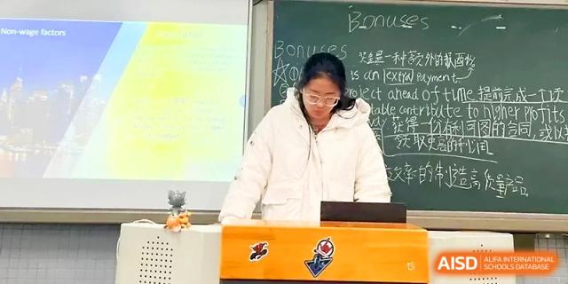A student focuses on a laptop while standing at the teacher's desk in a modern classroom at Zhengzhou No.1 High School