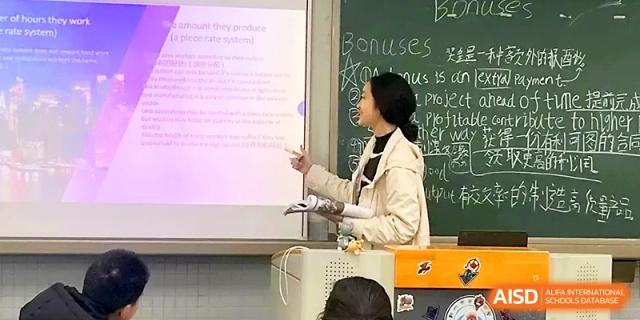 A female student uses a pointer to explain text on a projector screen during an academic presentation at Zhengzhou No.1 High School