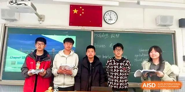 Three male students stand in front of a chalkboard and a national flag during a school presentation at Zhengzhou No.1 High School