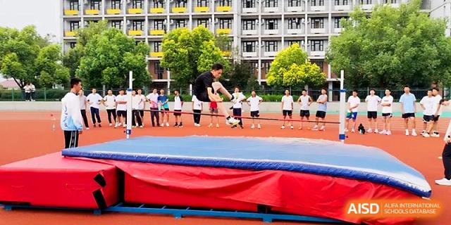 A student athlete successfully clears the high jump bar while others watch from the sidelines during a sports meet at Zhengzhou No.1 High School
