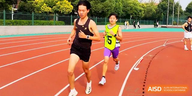 Two male students compete in a long-distance running race on a professional red track during a bright day at Zhengzhou No.1 High School