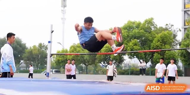 A student leaps through the air while attempting to clear the high jump bar during an intense competition at Zhengzhou No.1 High School