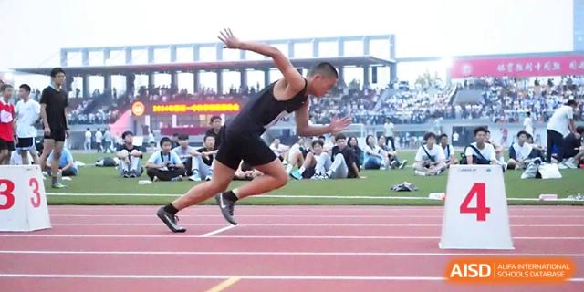 A side view of a student athlete in full sprint during a track and field competition on a sunny afternoon at Zhengzhou No.1 High School