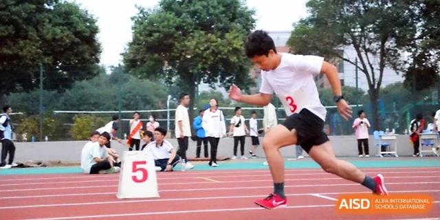A sprinter explosive starts from the blocks next to lane marker five during a competitive track race at Zhengzhou No.1 High School