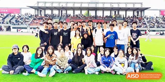 A large group of students and faculty members gather for a commemorative group photo on the outdoor bleachers at Zhengzhou No.1 High School