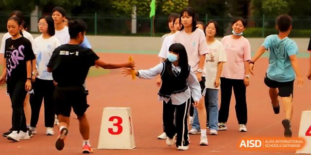 Two students successfully pass the baton during a relay race competition on the school running track at Zhengzhou No.1 High School
