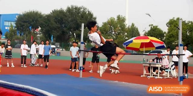 A focused student athlete jumps over the high jump bar during an outdoor sports competition on campus at Zhengzhou No.1 High School
