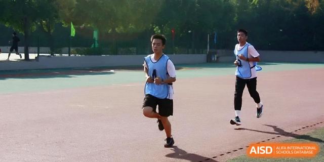 A young athlete in a blue shirt runs a race during the annual track and field games on a sunny day at Zhengzhou No.1 High School