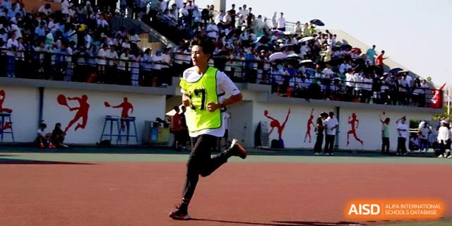 A student in a neon vest sprints down the final stretch of a race on the red athletic track at Zhengzhou No.1 High School