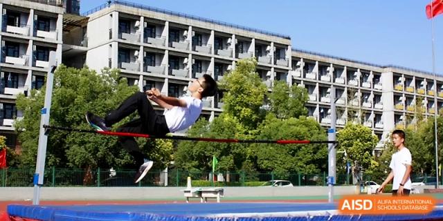An athlete performs a high jump back-flip technique to clear the bar during a competitive track meet at Zhengzhou No.1 High School