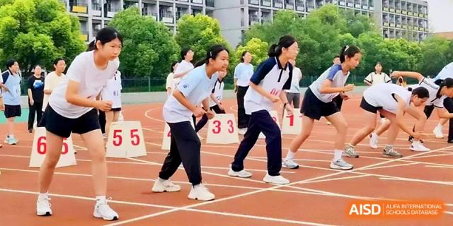 Two female students prepare at the starting line for a competitive race during an outdoor sports event at Zhengzhou No.1 High School