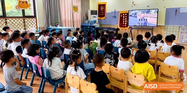 Primary students sit together in a cozy classroom setting while watching an educational video on a digital screen at Zhengzhou No.1&8 United International School