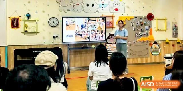 A female educator presents a slideshow to a group of parents and students in a modern classroom at Zhengzhou No.1&8 United International School