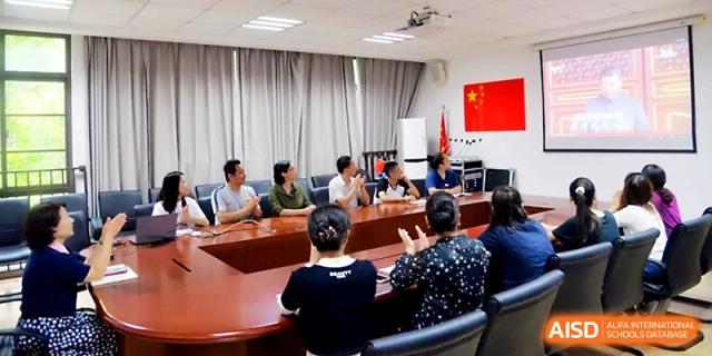 Faculty members and staff gather around a large conference table for a formal meeting in a well-lit boardroom at Zhengzhou No.1&8 United International School