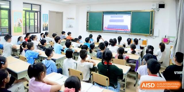 Primary students sit in a bright classroom while watching an educational presentation on a wall-mounted digital screen at Zhengzhou No.1&8 United International School
