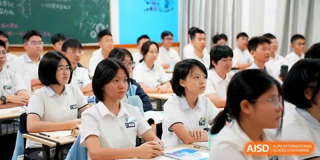 A group of female students in school uniforms listens intently during a collaborative classroom discussion at Zhengzhou No.1&8 United International School