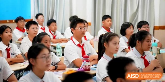 Students wearing red scarves and school uniforms participate in a focused study session at their desks at Zhengzhou No.1&8 United International School