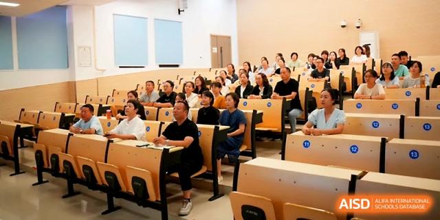 A group of parents and students sits in a tiered lecture hall for a school orientation or informational meeting at Zhengzhou No.1&8 United International School