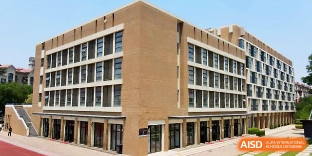 An exterior view of a multi-story modern brick academic building on the school campus under a bright sky at Zhengzhou No.1&8 United International School