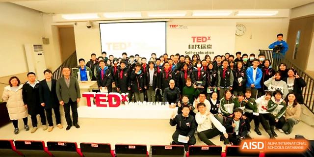 A large group of students and faculty members poses for a photo at a TEDx event held in the school auditorium at Zhengzhou No.1&8 United International School