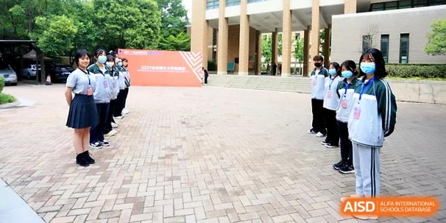 An outdoor courtyard with a large banner where students gather for a formal event or sports competition at Zhengzhou No.1&8 United International School