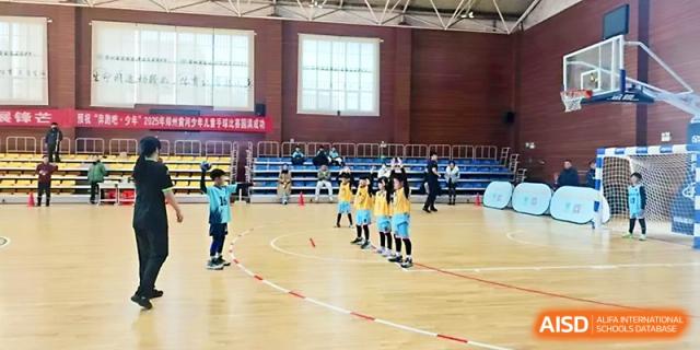 Young students in light blue basketball uniforms line up for a sports session on an indoor court at Zhengzhou No.1&8 United International School