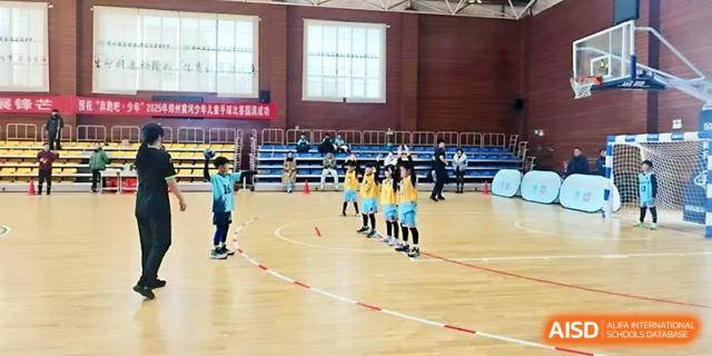 A student athlete practices basketball drills on a polished indoor wooden court at Zhengzhou No.1&8 United International School