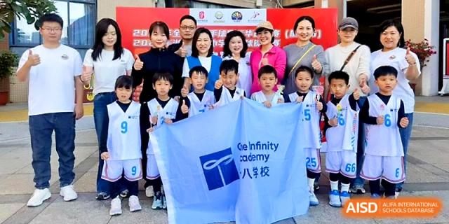 Students and faculty members pose together with a school flag during a sports celebration at Zhengzhou No.1&8 United International School