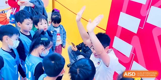 Children raise their hands with excitement during an engaging outdoor school activity at Zhengzhou No.1&8 United International School