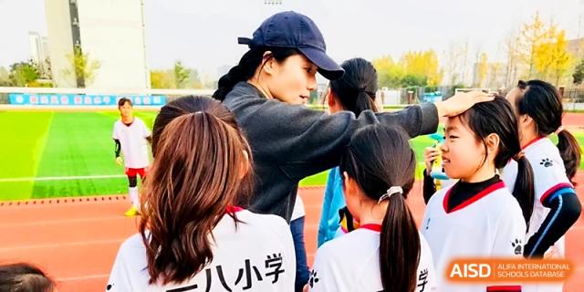 A coach provides guidance to a young student during an outdoor sports training session at Zhengzhou No.1&8 United International School