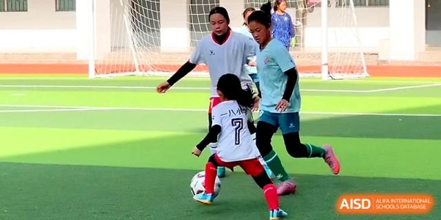 Two students engage in a competitive soccer match on a professional green turf field at Zhengzhou No.1&8 United International School