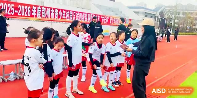Students in white sports uniforms discuss strategy during an outdoor athletic competition at Zhengzhou No.1&8 United International School