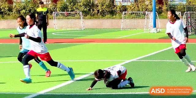 An action shot of a student athlete sliding to reach the ball during a soccer game at Zhengzhou No.1&8 United International School