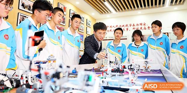 Students in uniform work together on a technical robotics or engineering project in a specialized lab at Zhengzhou No.4 Middle School