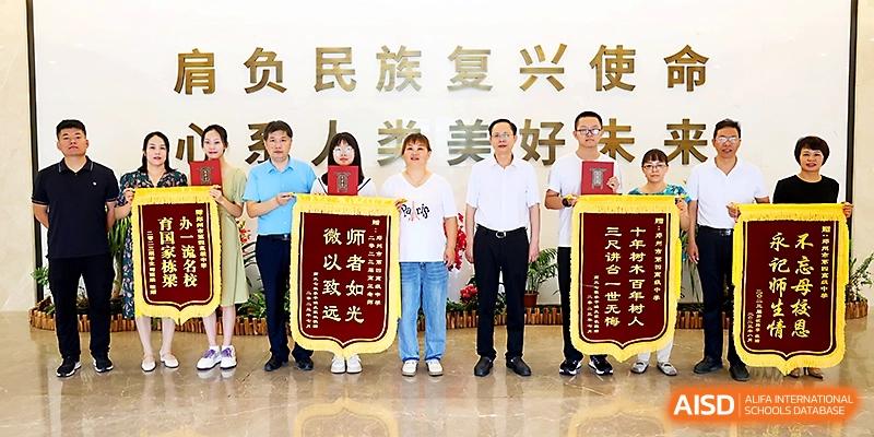 Students and staff holding honorary red awards and banners at Zhengzhou No.4 Middle School.