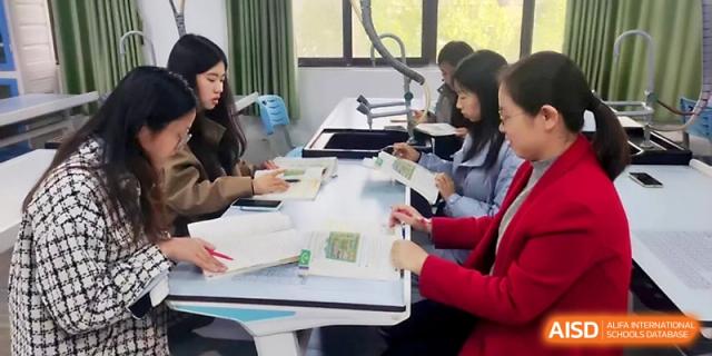 Staff members reviewing educational materials and notebooks together at Zhengzhou No.4 Middle School.