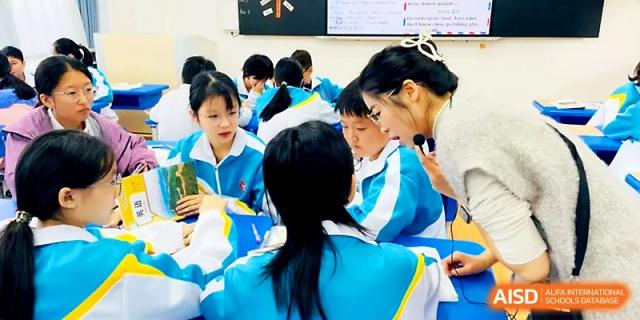 A teacher providing one-on-one guidance to students at their desks at Zhengzhou No.4 Middle School.