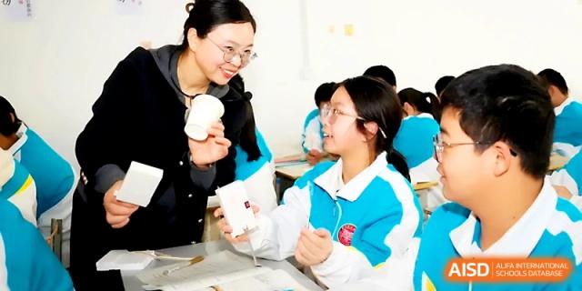 A teacher assisting a student with a science project involving cups at Zhengzhou No.4 Middle School.