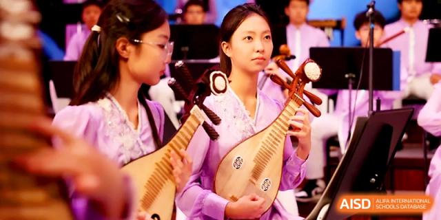A female student musician plays a traditional Pipa lute as part of a traditional orchestra at Zhengzhou No.4 Middle School.