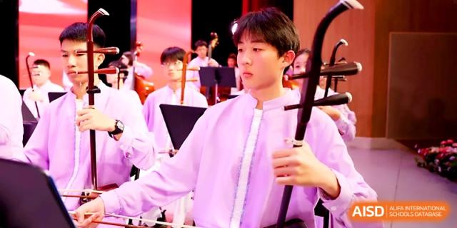 A young male student plays a traditional Chinese string instrument during a cultural performance at Zhengzhou No.4 Middle School.