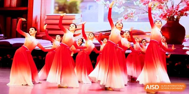 A group of dancers in vibrant red and white gradient costumes perform a graceful routine at Zhengzhou No.4 Middle School.