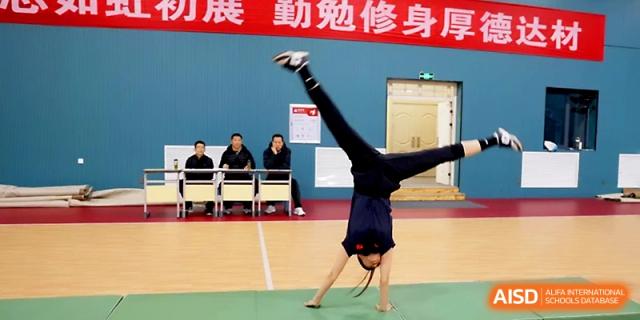 A student performs a dynamic handstand or cartwheel transition during a gymnastics display at Zhengzhou No.4 Middle School.