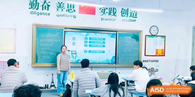 Students sit at their desks while a teacher uses a large digital screen to present a lesson in class at Zibo International Academy At Hi-Tech Zone.