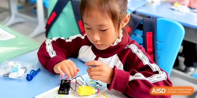 A student connects wires to a battery pack as part of a practical science project in class at Zibo International Academy At Hi-Tech Zone.