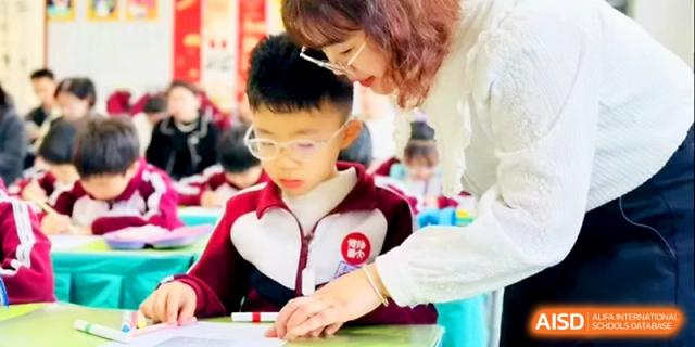 A teacher provides one-on-one guidance to a student working on a creative project in the classroom at Zibo International Academy At Hi-Tech Zone.
